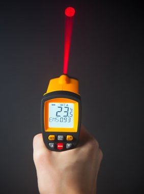 Infrarot Thermometer strahlt mit roten Laser an Wand